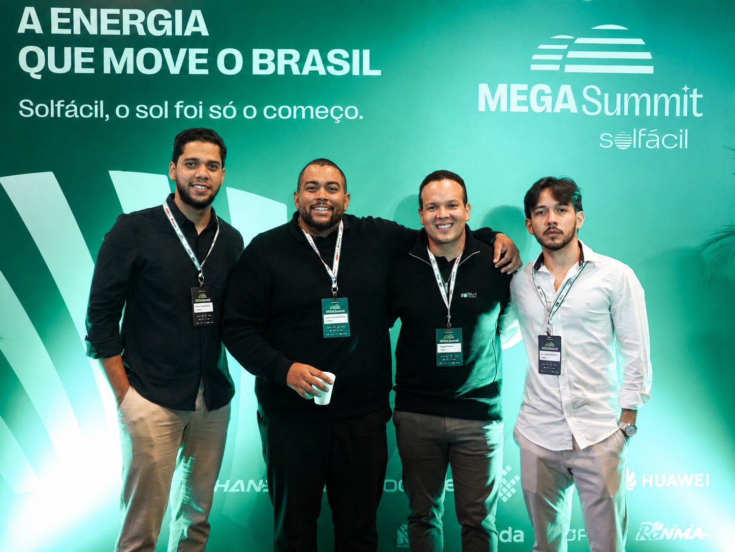Quatro integrantes da LIV Energia Solar lado a lado diante do painel do Mega Summit da Solfácil.
